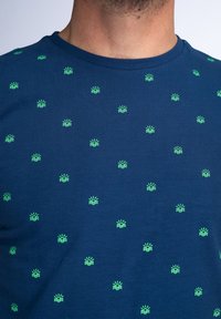 Tricou cu mânecă scurtă, de culoare albastru marin, cu un model repetat de soarele mici verzi și valuri. Fabricat dintr-un material moale și ușor.