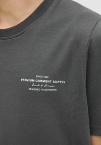 Gray t-shirt with a crew neck, featuring white text that reads "Premium Garment Supply" and "Designed in Denmark."