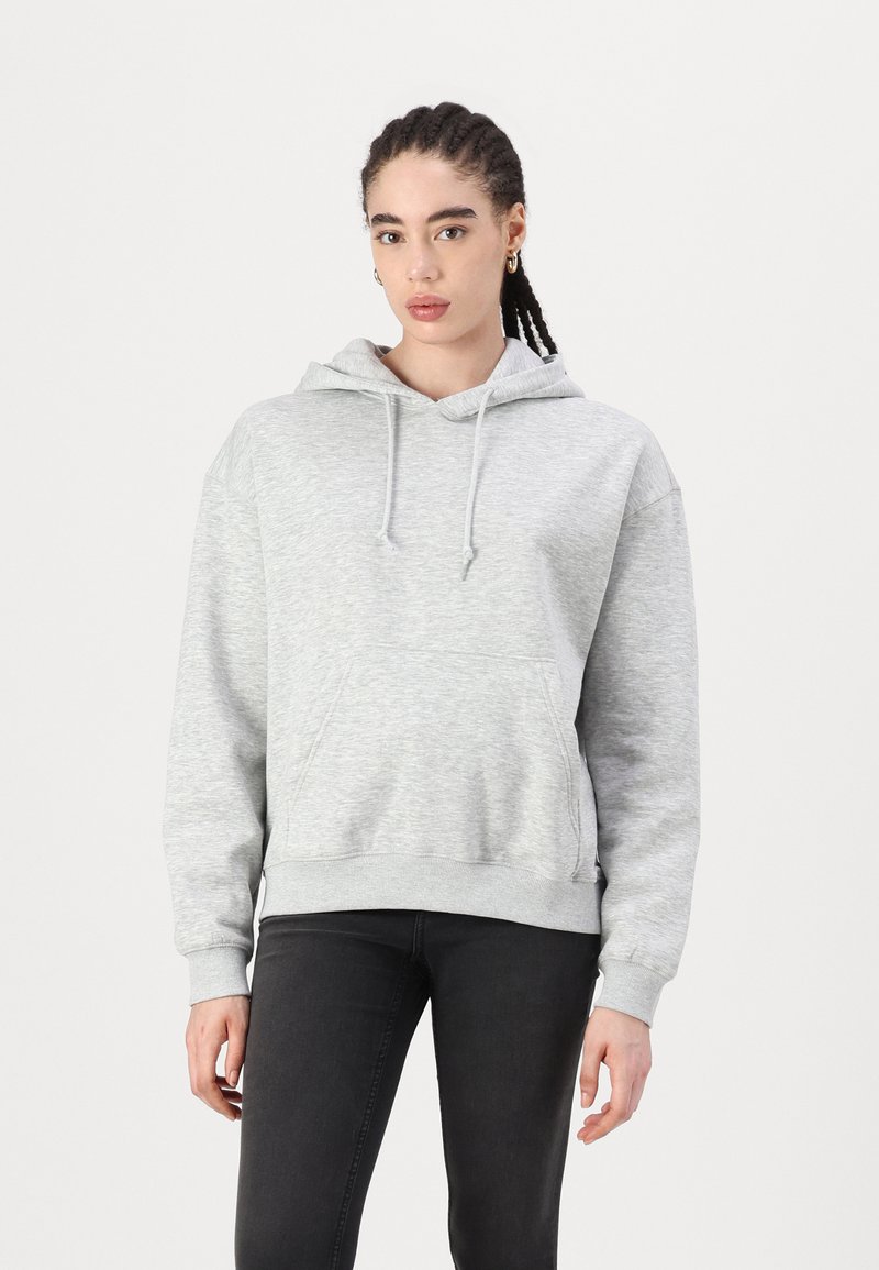 Gray hoodie in soft, textured fabric with a front pocket, drawstrings on the hood, and ribbed cuffs. Worn with black pants.