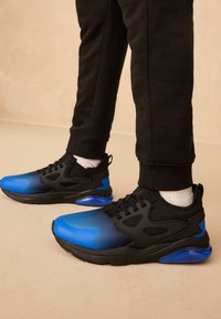 Zwarte sportschoenen met een blauw verloopontwerp, rubberen zool en een bovenwerk van mesh. Voorzien van gestructureerde accenten en een dempende luchtunit in de hiel.