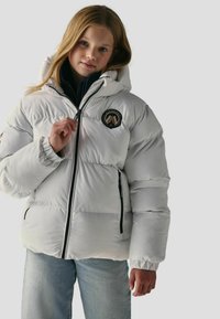 Giacca puffa bianca con cappuccio, dotata di zip frontale, polsini a coste e patch logo sul petto. Texture liscia, design isolato.