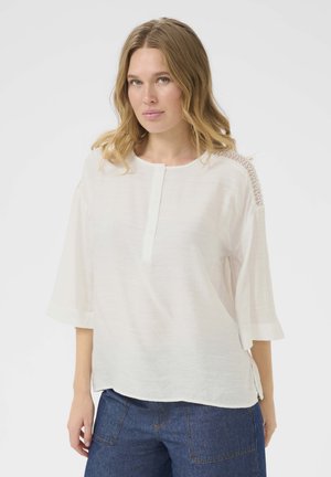 White, long-sleeve, lightweight blouse with a round neckline and button placket; features textured lace detail on the shoulders.