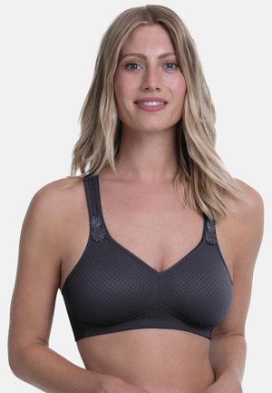 Donna sorridente con capelli biondi fino alle spalle che indossa un reggiseno wireless grigio scuro strutturato con decorazioni floreali sulle spalline.