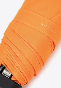 Pomarańczowy parasol z gładką powierzchnią materiału, ozdobiony przeszyciami i logo "WITTCHEN" na tkaninie. Widoczny czarny uchwyt.