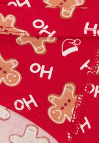 Czerwona tkanina z nadrukami piernikowych ludzików i białym napisem „OH”. Miękki materiał o gładkiej fakturze z kontrastującymi szwami.