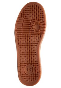 Rubber shoe sole in orange with a textured, patterned surface and circular emblem. Features grid and lines for grip and traction.
