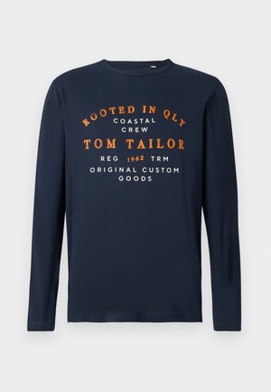 Marineblaue Langarmshirt mit Rundhalsausschnitt, bedruckt mit orangefarbenem und weißem Text: "VERWURZELT IN QLY COASTAL CREW TOM TAILOR 1962 ORIGINAL CUSTOM GOODS."