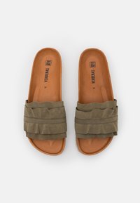 Sandalias de ante verde con tiras con volantes, plantillas de cuero marrón y una plantilla plana sencilla, etiquetadas como "VERBENAS 37" en el interior.