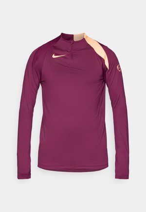 Tamsiai purpurinė ilgomis rankovėmis sportinė marškinėliai su aukštu gaubtu, kuriuose yra persikinė detalė ant peties ir mažas logotipas ant rankovės.