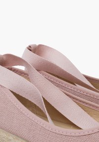 Růžové plátěné espadrilky s křížovými textilními popruhy, texturovaným svrškem, šitými detaily a přírodní jutovou podrážkou.