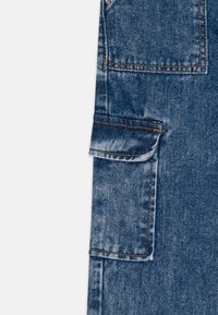 Pantalones cargo de mezclilla en azul medio con una textura rugosa, que presentan un bolsillo lateral, costuras dobles y dobladillo con puños.