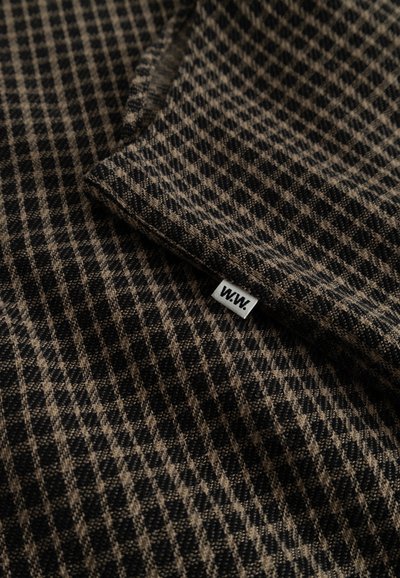 Fekete és barna kockás mintájú gyapjú keverék anyag. Hajtott széle és egy kis szőtt címke található rajta, amelyen a "W.W." felirat szerepel az alsó sarokban.