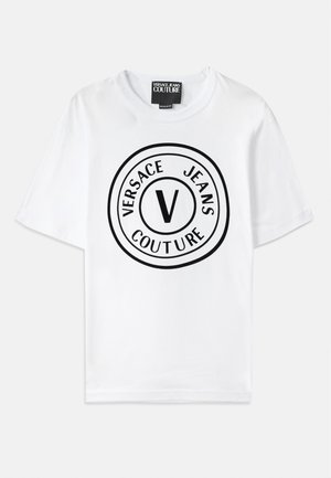 White cotton t-shirt featuring a circular black logo with "VERSACE JEANS COUTURE" text and a central "V." Crew neck, relaxed fit.