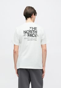 Λευκό βαμβακερό t-shirt με μαύρο γραφικό κείμενο και σχέδιο βουνού στην πλάτη. Κοντά μανίκια και κλασική εφαρμογή με ίσιο τελείωμα.