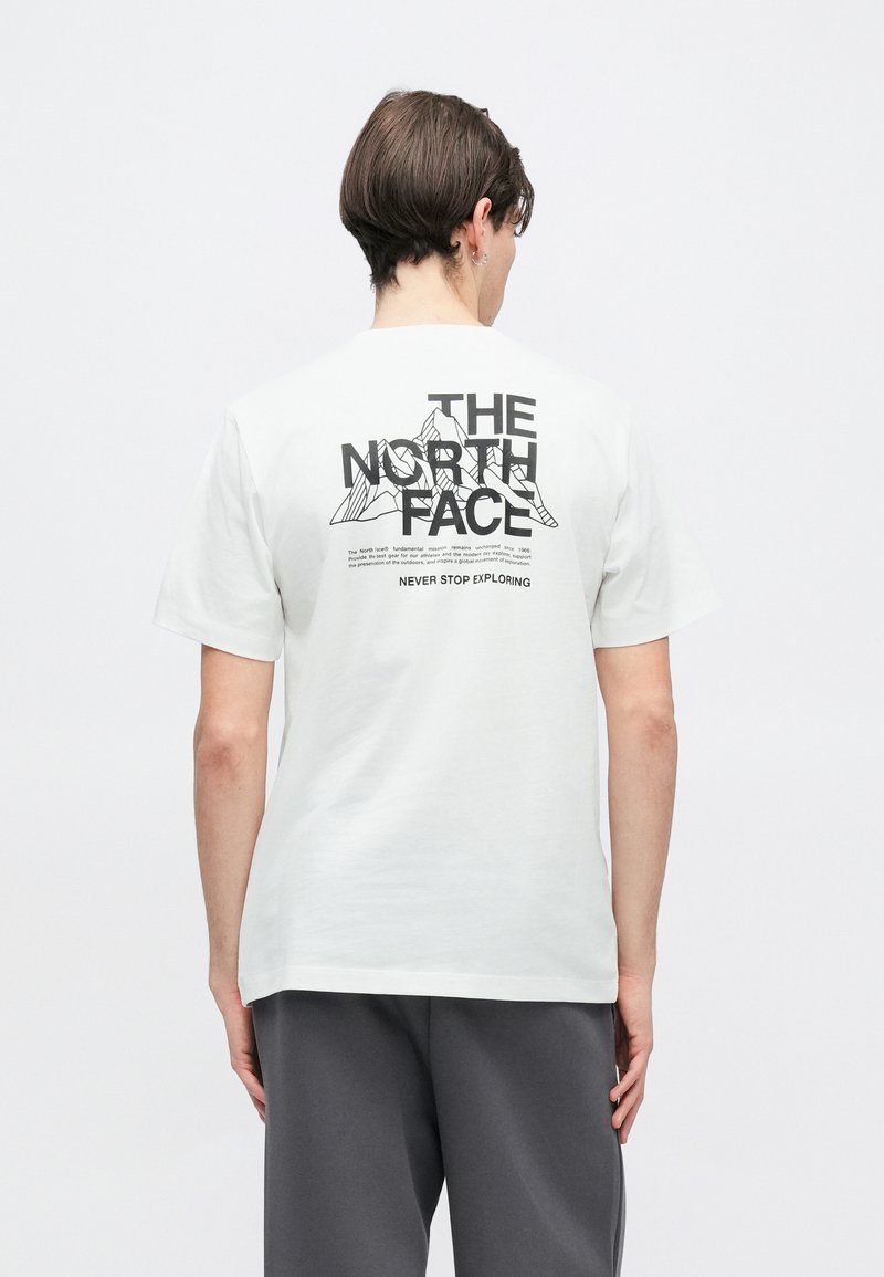 Λευκό βαμβακερό t-shirt με μαύρο γραφικό κείμενο και σχέδιο βουνού στην πλάτη. Κοντά μανίκια και κλασική εφαρμογή με ίσιο τελείωμα.