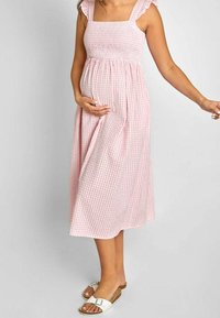 Rosa rutigt midiklänning med fyrkantig halsringning, rynkad bodice och volangremmar; bärs med vita sandaler med platt sula och en avslappnad passform.