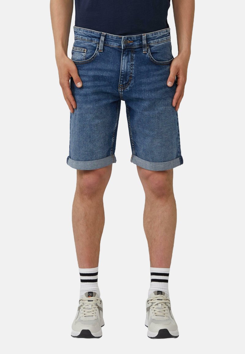 Shorts en denim bleu moyen avec des ourlets roulés, design cinq poches et coutures contrastantes. Associés à des baskets grises et des chaussettes rayées.