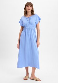 Light blue cotton midi dress with short sleeves, gathered waistband, and tie detail at neckline. Worn with tan flat sandals.