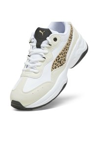 Vit och beige Puma-sneaker med svart sula, vita snören, svart tungmärke och leopardmönster på sidan.