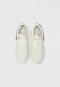 Λευκά δερμάτινα αθλητικά παπούτσια χαμηλού ύψους με λευκά κορδόνια και λεπτομέρεια ασημένιας αλυσίδας, απεικονισμένα από πάνω σε λευκό φόντο.