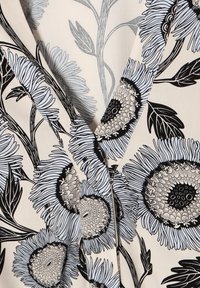 Abito a portafoglio floreale con fondo crema, decorato con motivi floreali blu e neri, tessuto strutturato e scollatura a V profonda.