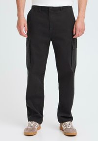 Black cotton cargo pants featuring two side pockets, straight leg design, and a button closure. Worn with gray sneakers.