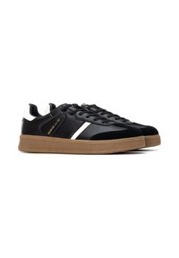 Zapatillas negras con materiales de cuero y ante, que presentan una raya blanca y una suela de goma. Detalles perforados en los laterales.