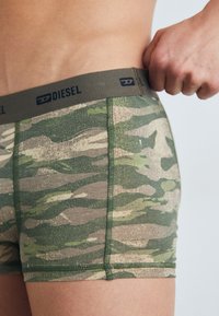 Zöld és bézs mintázatú, puha anyagból készült kamuflázs boxeralsó, bézs színű, rugalmas derékpánttal, amelyen a Diesel logo látható.
