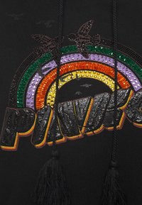 Hoodie noir présentant un design coloré en arc-en-ciel avec des sections orange, violet, vert et jaune, agrémenté de perles brillantes et de franges noires.