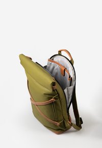 Zaino verde oliva con dettagli in pelle color cuoio, compartimento principale con zip e interno foderato con motivo a griglia grigia. Spallacci regolabili.