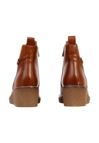 Bottes basses en cuir synthétique marron avec un bout arrondi, une semelle texturée marron clair et un petit bouton décoratif sur le côté.