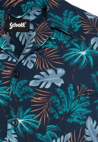 Korte mouwen overhemd met knopen in diep marineblauw, met een tropisch bladerenpatroon in teal en oranje. De stof is lichtgewicht met een zachte textuur.