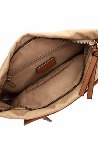 Interno di una borsa tote beige con una cerniera marrone, una piccola tasca con zip e due scomparti aperti. Presenta un'etichetta in pelle e un rivestimento testurizzato.