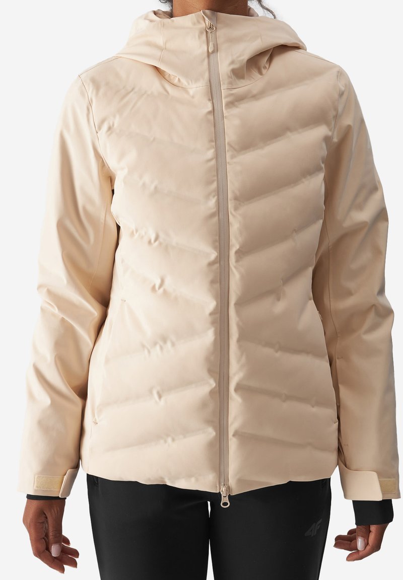 Béžová zateplená bunda s kapucí, s flešným zapínáním, texturovaným vzorem do šípů a elastickými manžetami. Hladký, vodoodpudivý materiál.