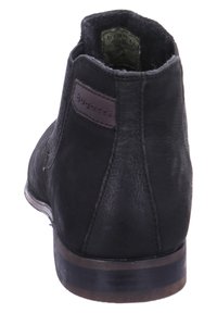 Bottine en cuir noir à finition lisse, bout arrondi, avec un logo accent marron sur le talon. Talon en bois empilé pour une stabilité accrue.