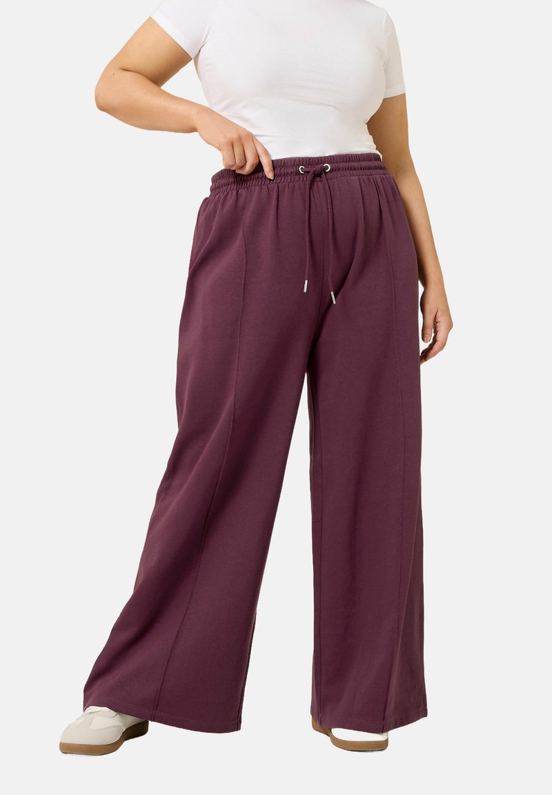 Weite Hose in einem tiefen Burgunderrot, aus weichem Material mit elastischem Bund und Kordelzug, im legeren Schnitt und mit seitlichen Taschen.