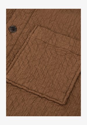 Gevoerde bruine stof met ruitenstiksel, voorzien van een rechthoekige zak en een donkerbruine knop.