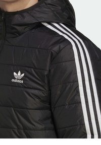Svart puffjacka med huva, med en silverfärgad Adidas-logotyp på bröstet och tre vita vertikala ränder längs axlarna.