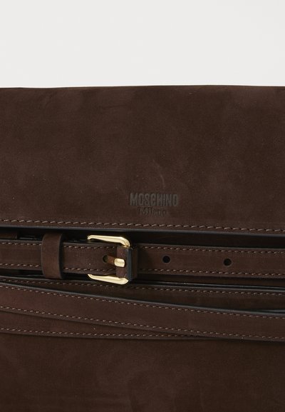 Bolso de ante marrón con un cierre en tono dorado y acentos en cuero negro. Branding de Moschino notable en la superficie. Acabado texturizado.