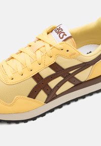 Baskets jaunes avec des accents marron, fabriquées en matériau en maille et synthétique. Présentent des superpositions texturées, un col rembourré et un système de fermeture à lacets.