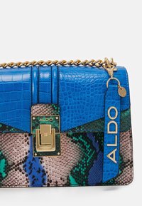 Niebieska torebka ze skóry z fakturą wytłoczoną imitującą skórę krokodyla, złote okucia oraz wzór węża w kolorach zielonym i beżowym. Posiada łańcuszkowy pasek.