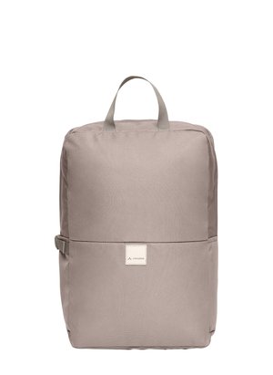 Sac à dos rectangulaire beige avec poignée supérieure, boucle latérale et patch logo à l'avant portant l'inscription "Vaude".