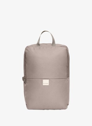 Sac à dos rectangulaire beige avec poignée supérieure, boucle latérale et patch logo à l'avant portant l'inscription "Vaude".