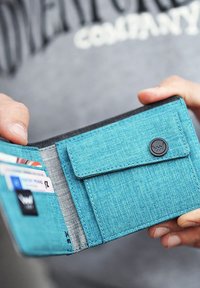 Blue fabric wallet with a textured surface, featuring several card slots and a button closure. Interior has a grey lining.