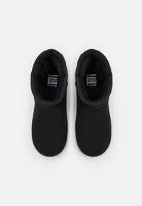 Schwarze Knöchelstiefel mit einer glatten Außenseite, weich gefüttertem Innenfutter aus Fleece, runder Zehenform und dekorativen Nähten entlang des oberen Randes.