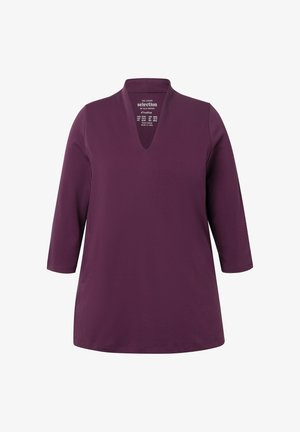 Lilla tunika med v-udskæring og trekvartærmer. Fremstillet af et blødt stof, har den en afslappet pasform og en glat tekstur.