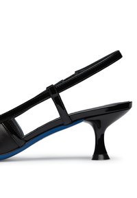 Tacco in vernice nera con silhouette curvata, sottile cinturino per la caviglia e accento blu sulla suola. Presenta un tacco in stile retro unico.