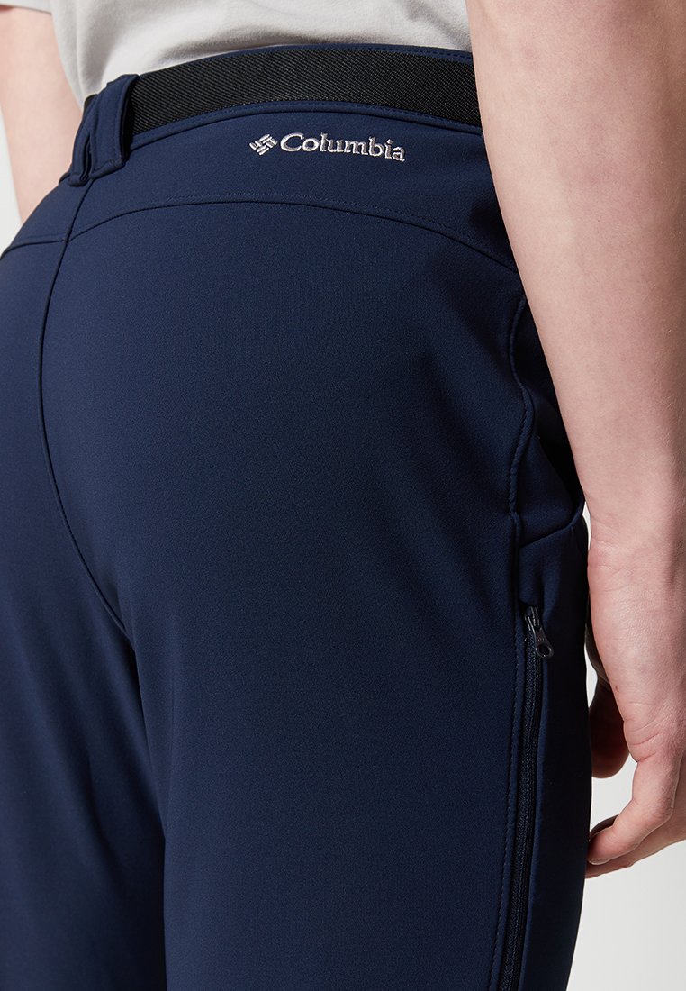 Pantalones exteriores azul marino hechos de tejido elástico, con una cinturilla negra, bolsillos con cremallera y un logo de Columbia bordado en la parte posterior.