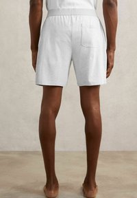 Jasnoszare bawełniane szorty z elastycznym pasem, jedną tylną kieszenią i luźnym krojem, zaprezentowane z tyłu.