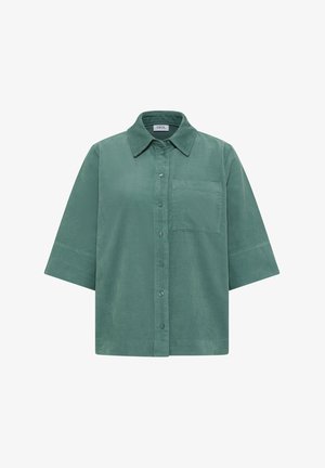 Chemise à manches courtes en velours côtelé vert doux, avec un devant à boutons, un col et une poche poitrine. Texture lisse avec un léger relief.